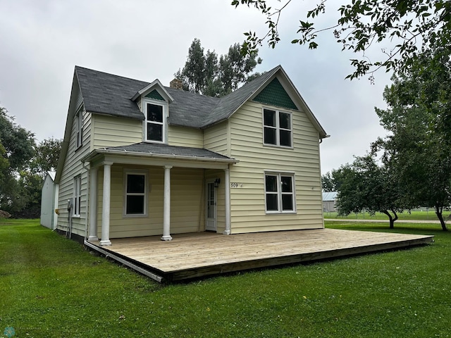 rear view of property with a deck, a yard, and roof with shingles