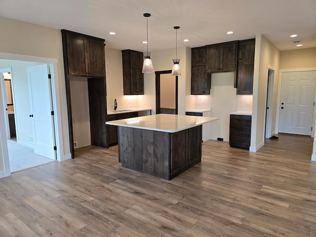 kitchen featuring light hardwood / wood-style flooring, dark brown cabinets, sink, pendant lighting, and a kitchen island