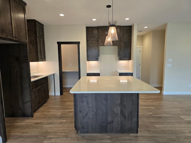 kitchen featuring dark brown cabinets, hanging light fixtures, a center island, and wood-type flooring