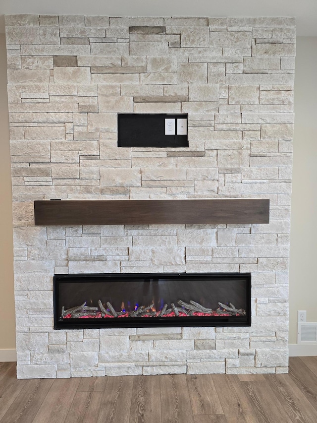 interior details with hardwood / wood-style floors and a stone fireplace