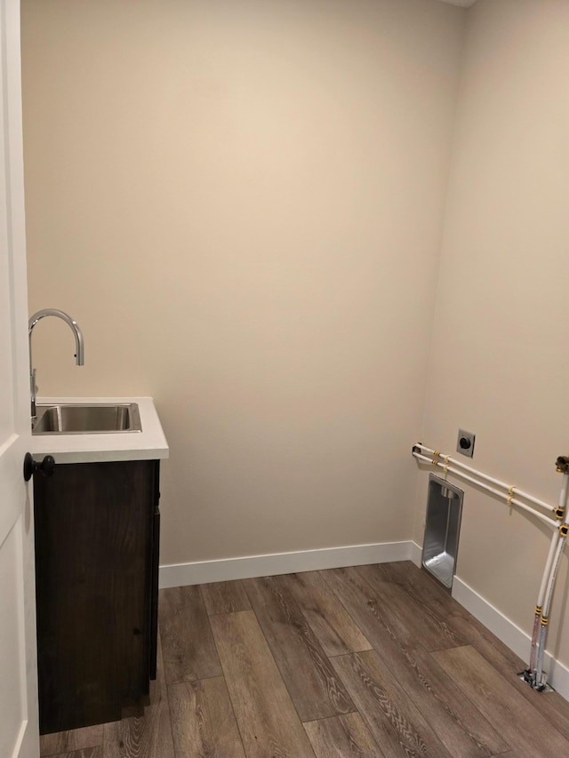 clothes washing area with sink, electric dryer hookup, and hardwood / wood-style floors