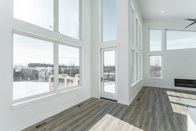 doorway to outside featuring plenty of natural light, hardwood / wood-style flooring, and a towering ceiling