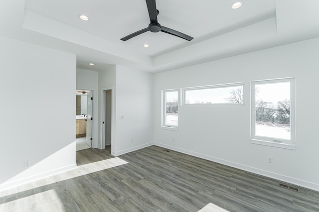 spare room with ceiling fan, wood-type flooring, and a tray ceiling