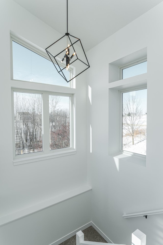 unfurnished dining area with a notable chandelier, a wealth of natural light, and carpet flooring