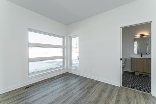 unfurnished bedroom with sink, hardwood / wood-style flooring, and connected bathroom