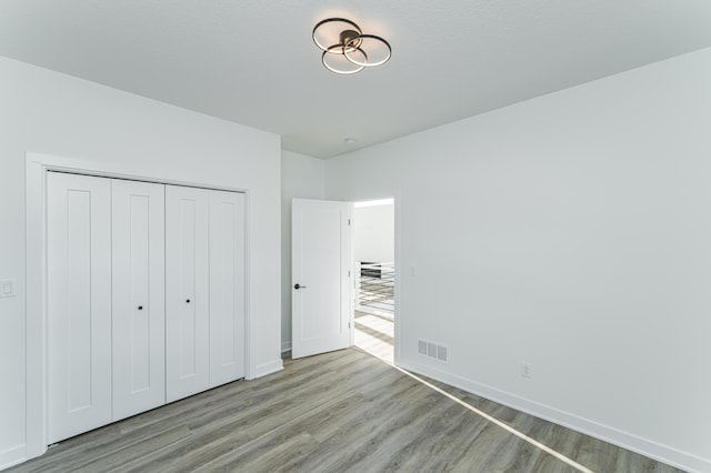 unfurnished bedroom featuring wood-type flooring and a closet