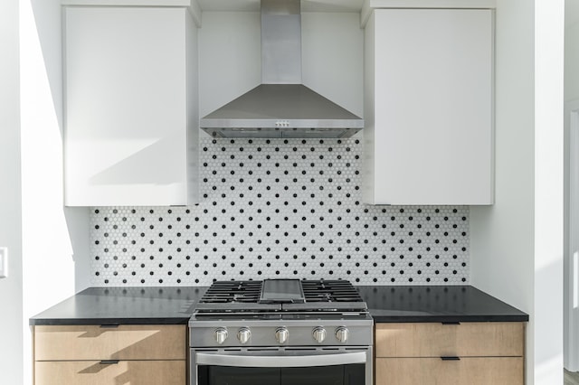 kitchen featuring wall chimney range hood, tasteful backsplash, light brown cabinetry, and stainless steel gas range