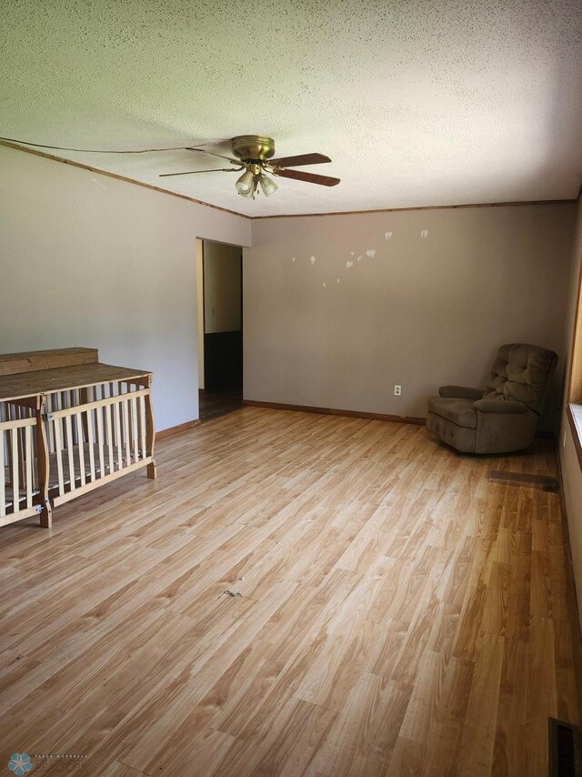 interior space with ceiling fan, light wood-type flooring, and a textured ceiling