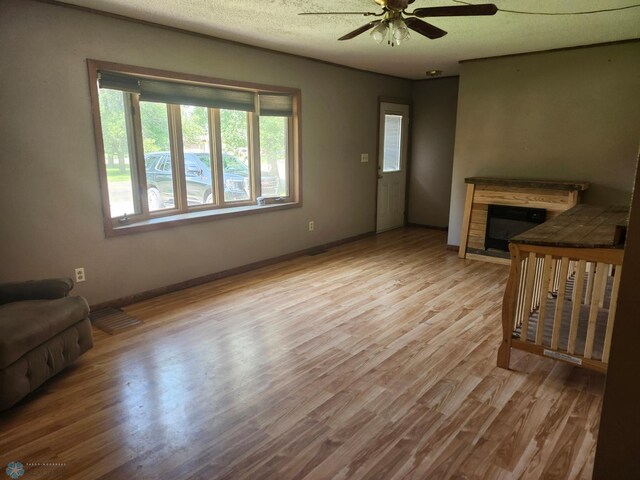 living room with ceiling fan, light hardwood / wood-style flooring, and a textured ceiling