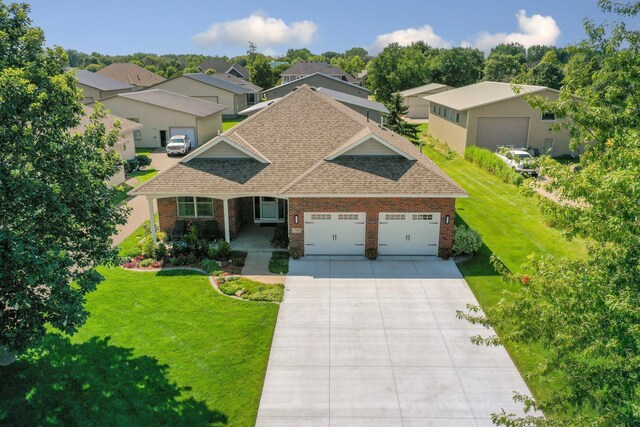 view of front of property featuring a shingled roof, a residential view, an attached garage, a front yard, and brick siding