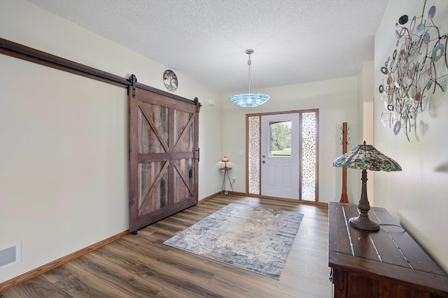 foyer with visible vents, wood finished floors, baseboards, and a textured ceiling