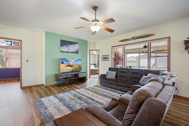 living room with a ceiling fan, wood finished floors, baseboards, and a textured ceiling