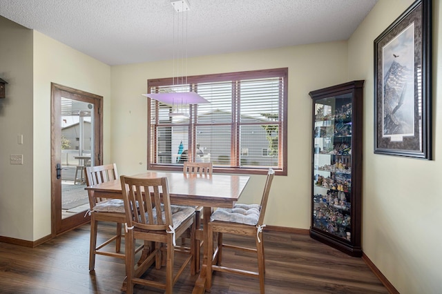 dining room featuring dark wood-type flooring, baseboards, and a textured ceiling