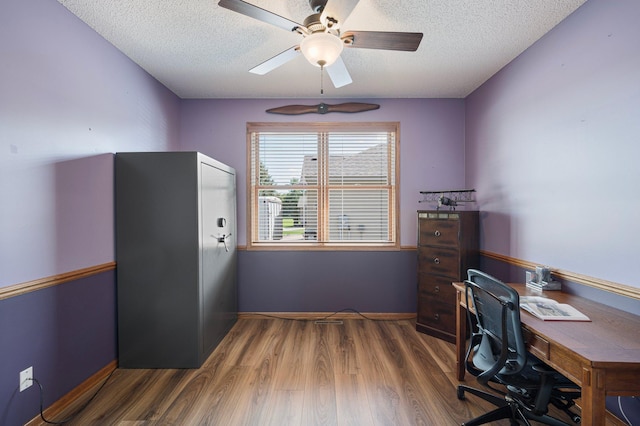 home office featuring a ceiling fan, wood finished floors, baseboards, and a textured ceiling