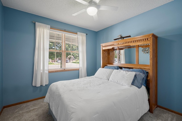 carpeted bedroom with a textured ceiling, baseboards, and a ceiling fan