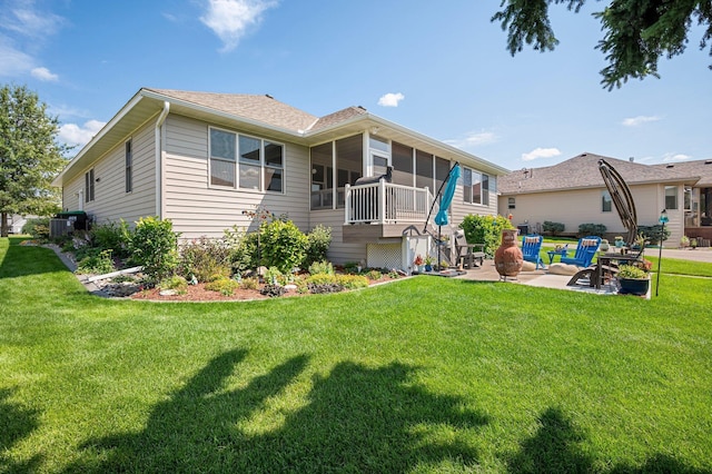 rear view of property with a yard, a sunroom, roof with shingles, and a patio area