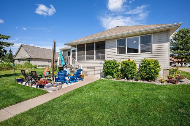 rear view of house featuring a yard, a patio area, a sunroom, and a shingled roof