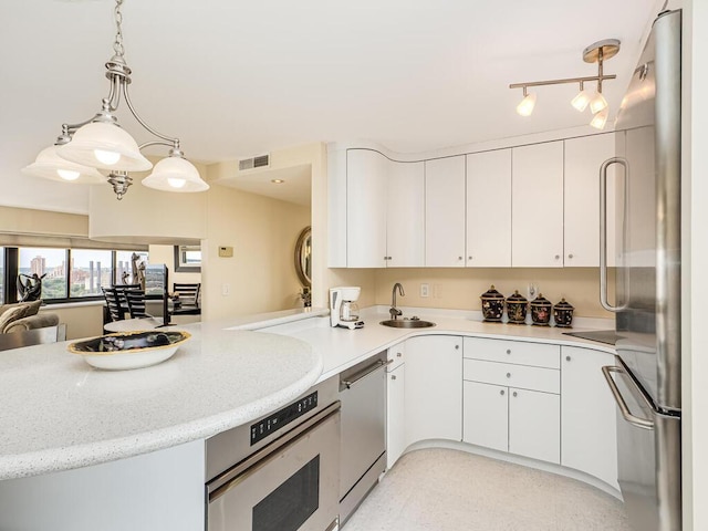 kitchen featuring white cabinets, decorative light fixtures, kitchen peninsula, and stainless steel appliances