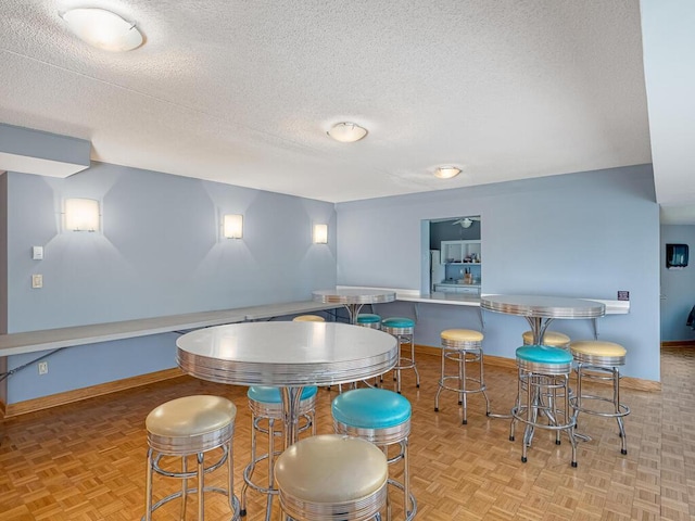 dining space with a textured ceiling and light parquet floors