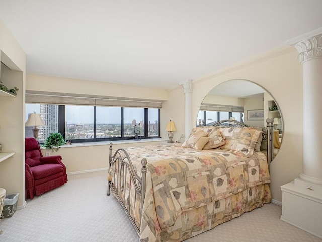 bedroom with ornate columns, a city view, and light colored carpet