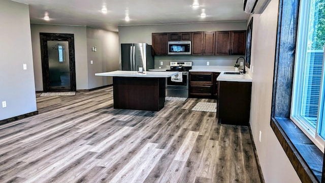 kitchen featuring light wood-type flooring, sink, a kitchen island, appliances with stainless steel finishes, and a wall mounted air conditioner