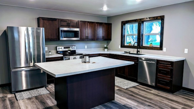 kitchen featuring appliances with stainless steel finishes, a kitchen island, dark brown cabinets, hardwood / wood-style floors, and sink