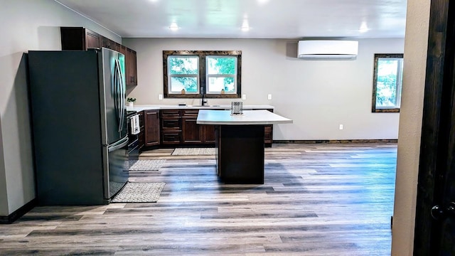 kitchen featuring stainless steel fridge, a center island, a wall mounted air conditioner, and plenty of natural light