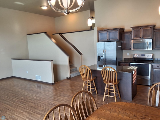 915 30th Ave W, West Fargo, ND 58078 - kitchen featuring stainless steel appliances, a center island, dark brown cabinetry, dark wood finished floors, and dark stone countertops