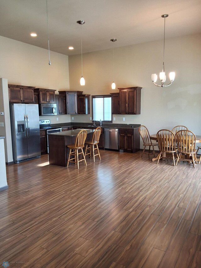 915 30th Ave W, West Fargo, ND 58078 - kitchen featuring appliances with stainless steel finishes, dark countertops, dark wood-style flooring, dark brown cabinets, and a high ceiling