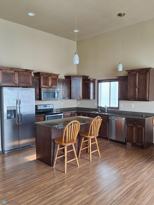 915 30th Ave W, West Fargo, ND 58078 - kitchen with stainless steel appliances, wood finished floors, a center island, a kitchen bar, and pendant lighting