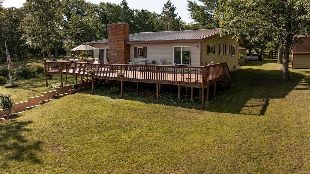 rear view of house featuring a wooden deck and a lawn