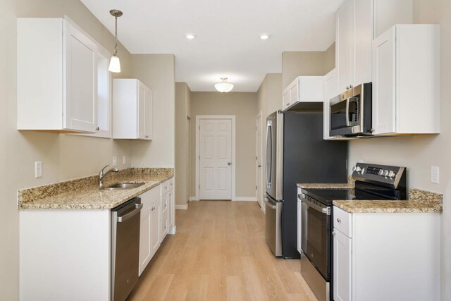 kitchen featuring sink, hanging light fixtures, light hardwood / wood-style floors, stainless steel appliances, and white cabinets