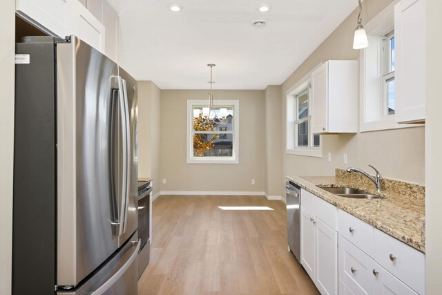 kitchen featuring stainless steel appliances, hanging light fixtures, sink, and white cabinets