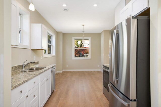 kitchen featuring sink, white cabinets, decorative light fixtures, and stainless steel appliances