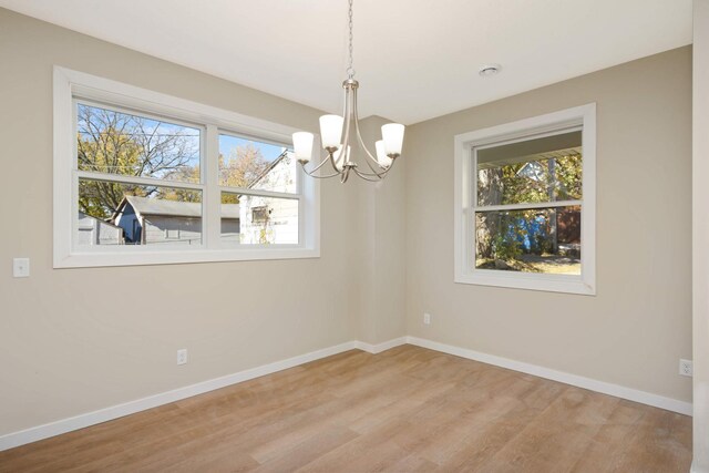 unfurnished dining area with an inviting chandelier and light hardwood / wood-style flooring