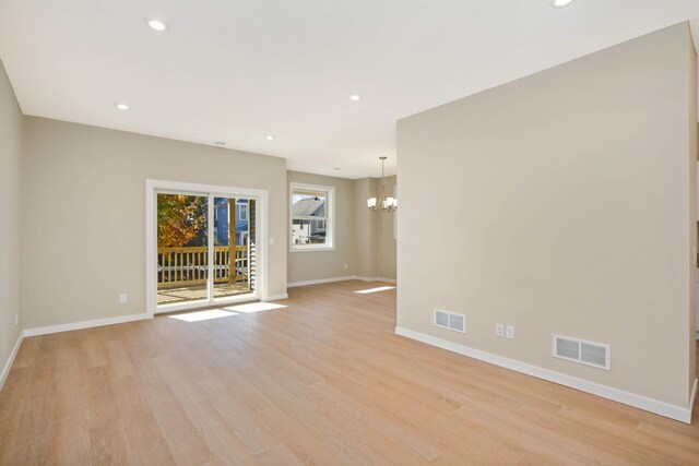 spare room featuring an inviting chandelier and light wood-type flooring