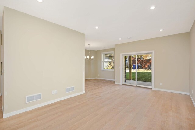 unfurnished room with an inviting chandelier and light wood-type flooring