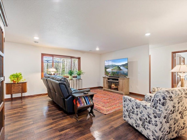 living room featuring recessed lighting, a warm lit fireplace, dark wood finished floors, and baseboards