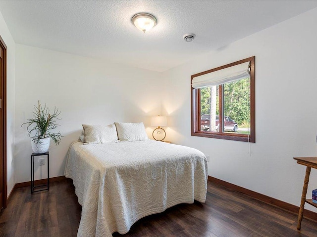 bedroom with dark wood-style floors, visible vents, a textured ceiling, and baseboards