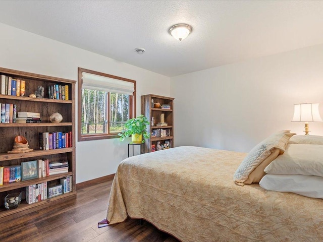 bedroom with baseboards and dark wood-type flooring