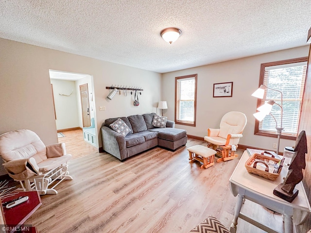 living room with light wood-type flooring, a textured ceiling, and a healthy amount of sunlight