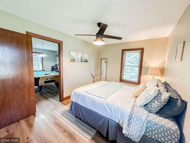 bedroom with multiple windows, light wood-type flooring, billiards, and ceiling fan