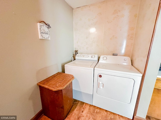 clothes washing area with light hardwood / wood-style floors and washing machine and dryer