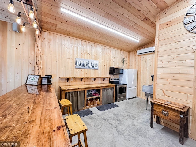 interior space with stainless steel appliances, wooden walls, lofted ceiling, and a wall unit AC