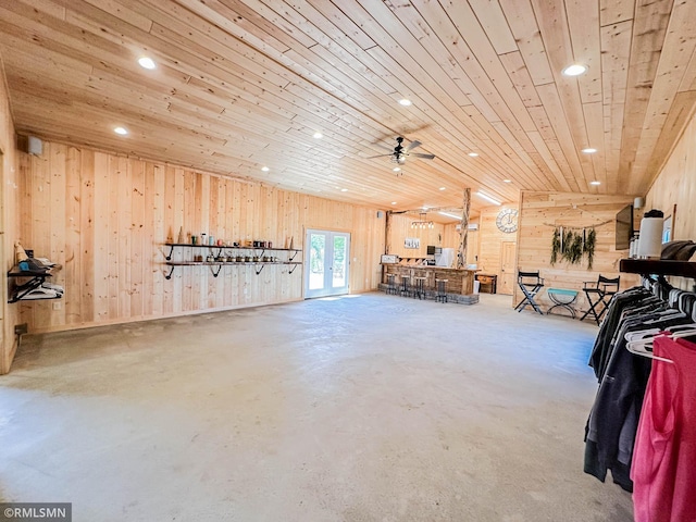 interior space featuring ceiling fan, wood walls, and wooden ceiling