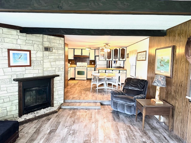 living room featuring wood walls, beamed ceiling, a fireplace, and hardwood / wood-style flooring