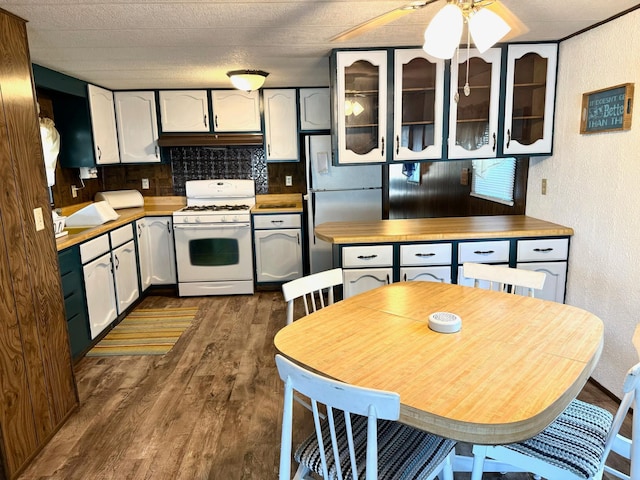 kitchen featuring dark hardwood / wood-style flooring, decorative backsplash, ceiling fan, white range with gas stovetop, and stainless steel refrigerator