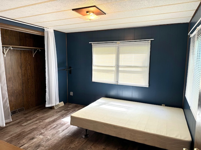 unfurnished bedroom featuring a textured ceiling, hardwood / wood-style flooring, and a closet