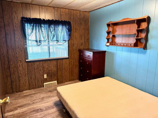 2769 28th St NW Unit 140, Wheeler Twp, MN 56623 - bedroom featuring wood walls, wood finished floors, and visible vents