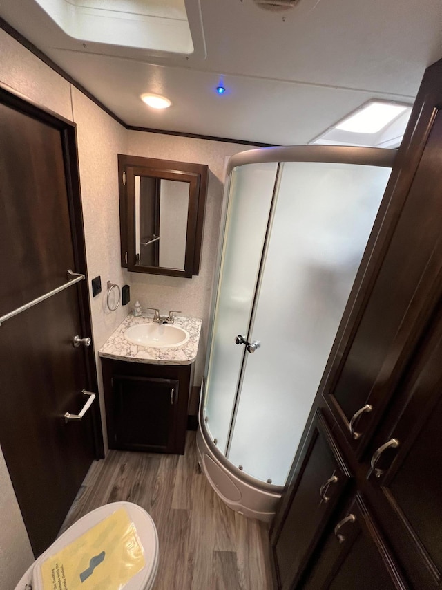 full bath with a stall shower, vanity, wood finished floors, ornamental molding, and a textured wall